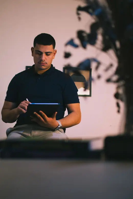 Felipe sentado no consultório, desenhando no tablet